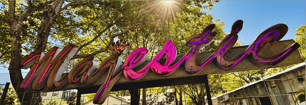 Neon 'Majestic' sign with sunlight filtering through trees in the background.